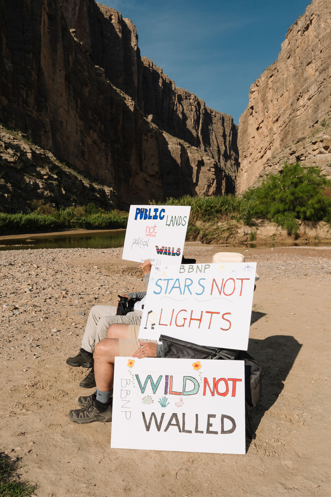 Protesters shield themselves from the sun with thier protest signs. Wednesday, Aug. 12, 2026.